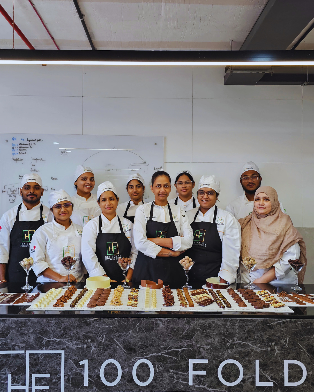 Students enrolled in a baking diploma in Hyderabad presenting professional handmade chocolates and pastry creations at 100 Folds Culinary Guild.