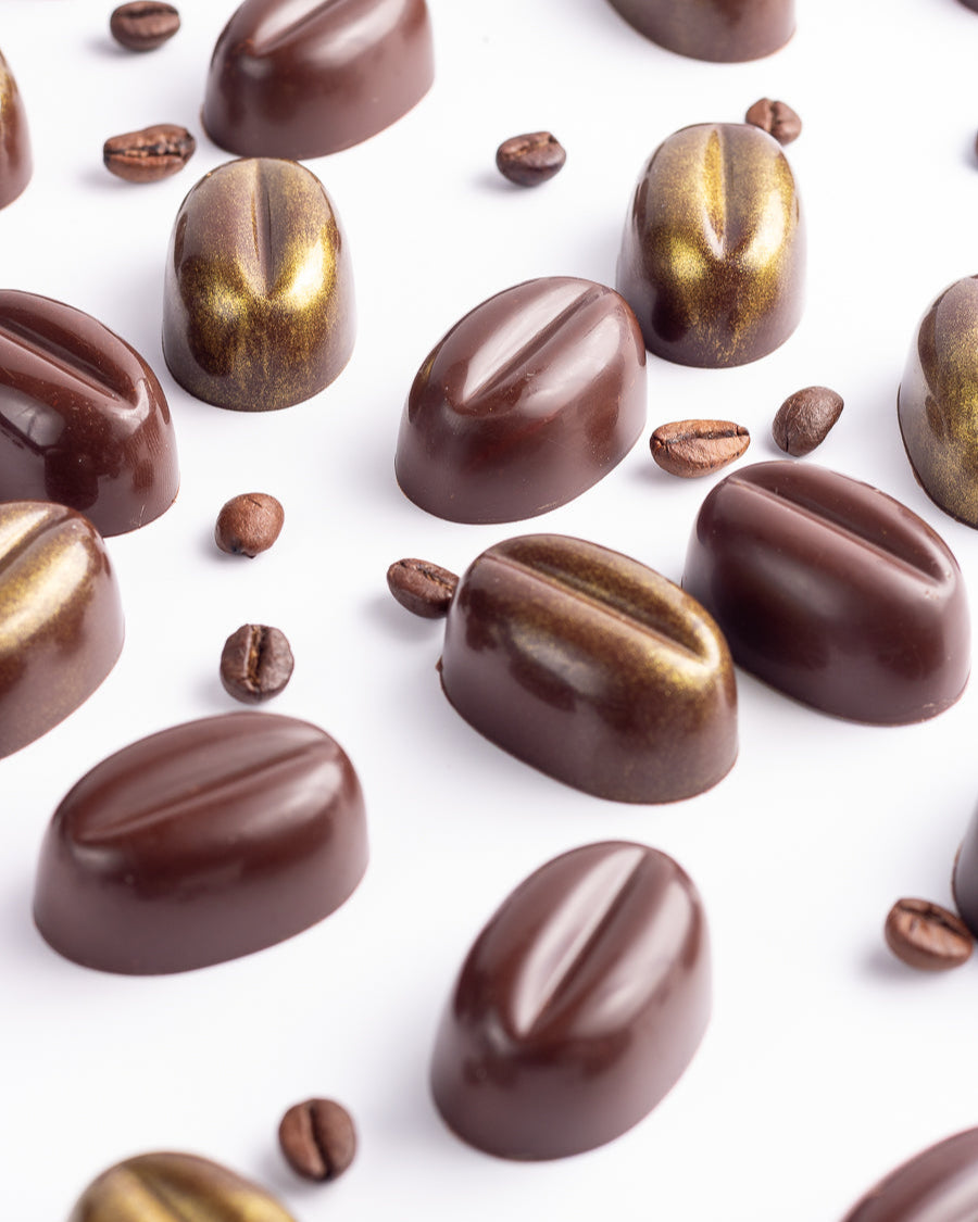 Chocolate candies shaped like coffee beans on a white background