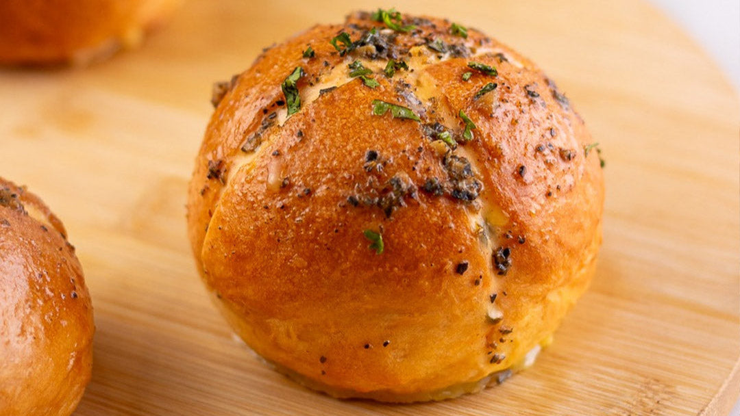 Baked bread roll with herbs on a wooden surface