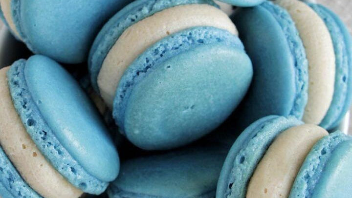 Blue and white macarons in a bowl with text overlay about an Italian method macaron recipe.