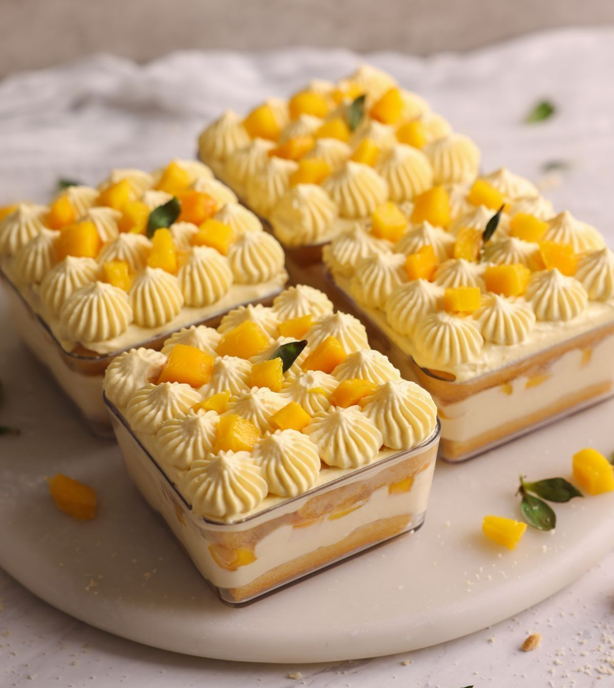 Three square desserts with yellow topping on a marble surface